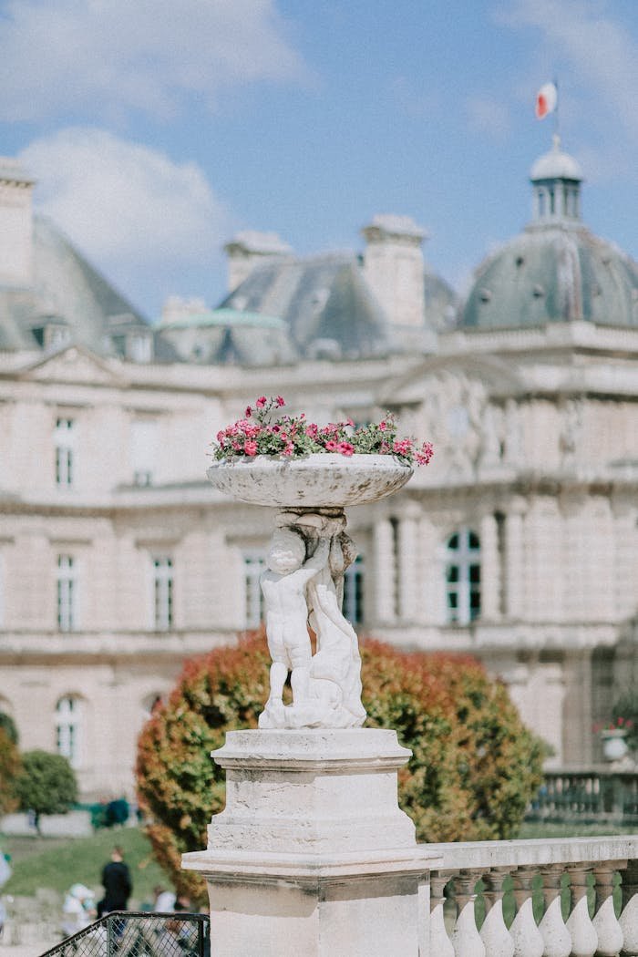 Luxembourg Palace and gardens feature a classic stone sculpture with blooming flowers.