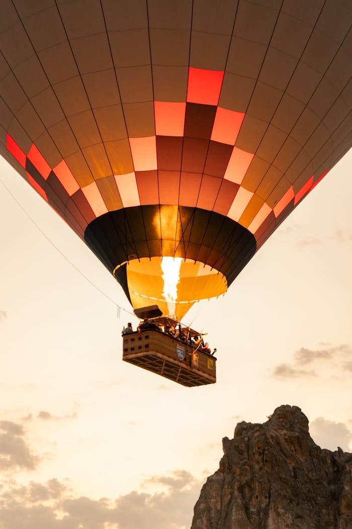 Scenic hot air balloon flight over a rocky cliff during sunset, highlighting adventure and travel.